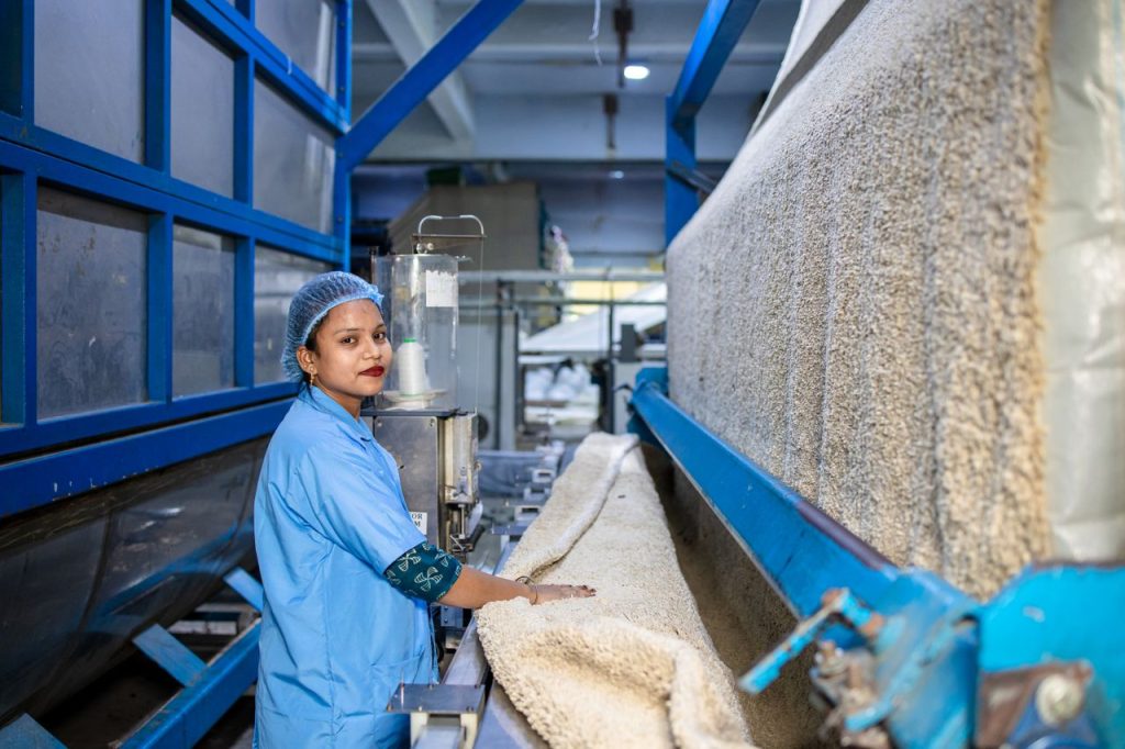 team-01 A skilled female worker operating textile machinery in a factory setting.