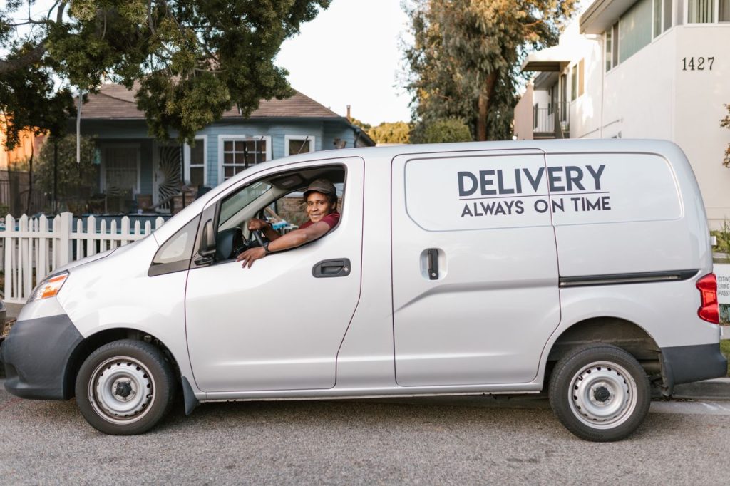 team-04 Courier driving a delivery van with 'Always On Time' service slogan parked in neighborhood.